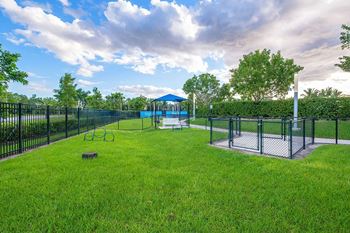 A fenced in dog park with a playground and a gazebo